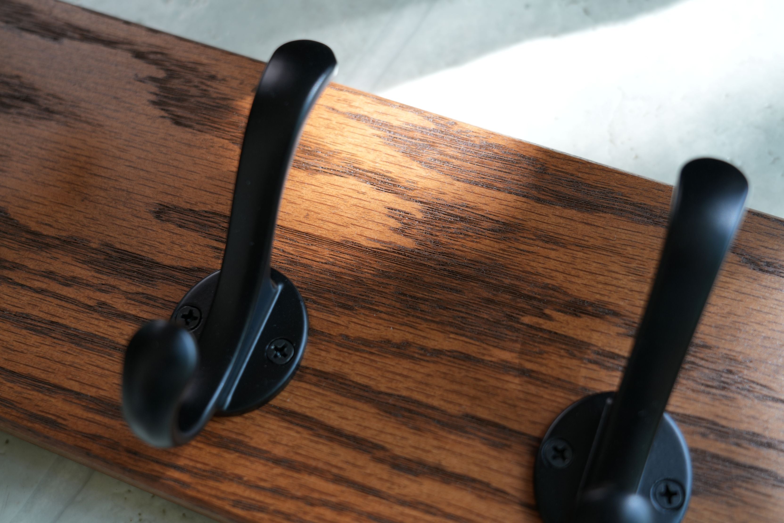 Two black hooks on a wooden surface