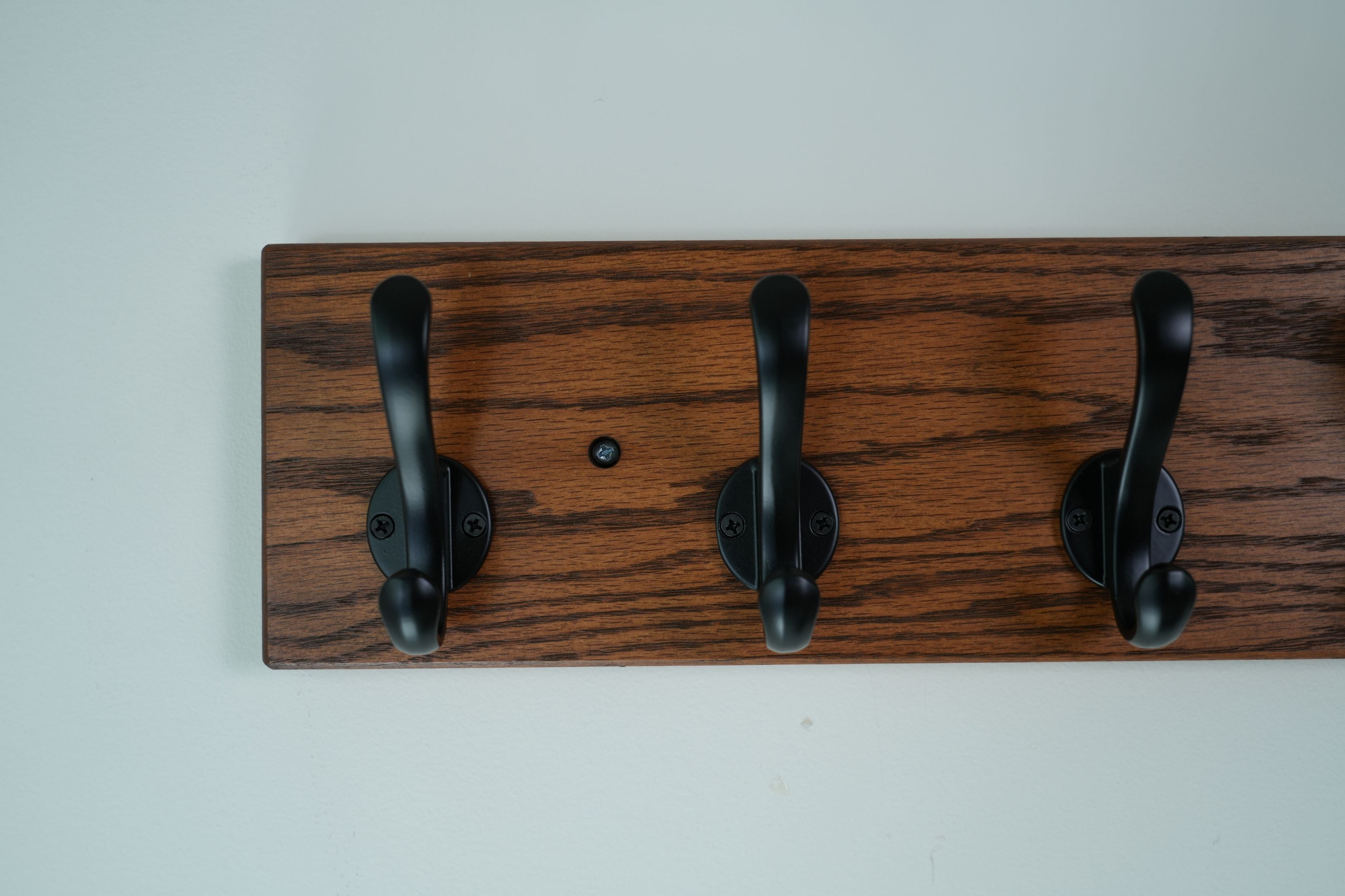 Wooden wall hook with three black hooks on a white background