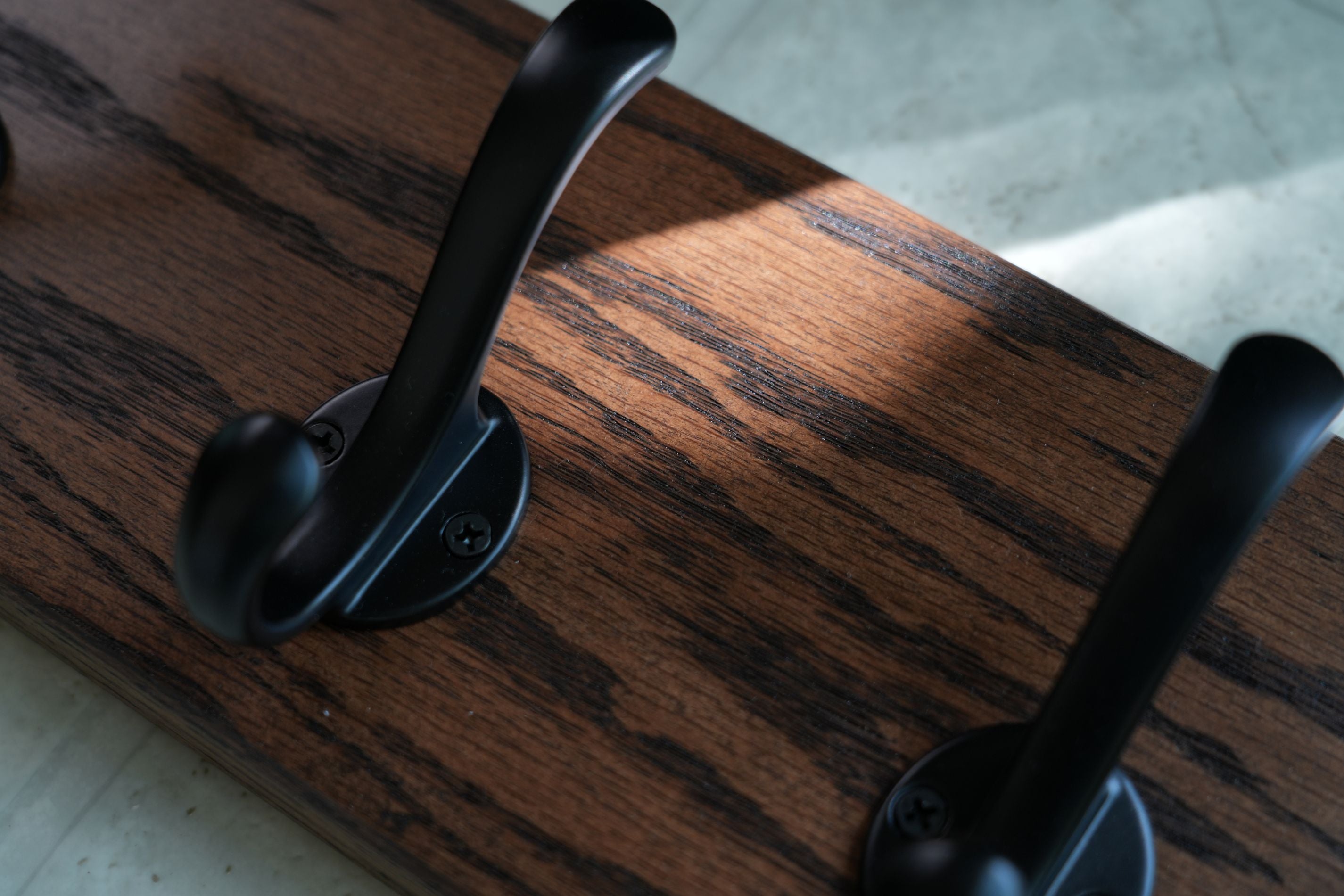 Two black hooks on a wooden surface with a blurred background