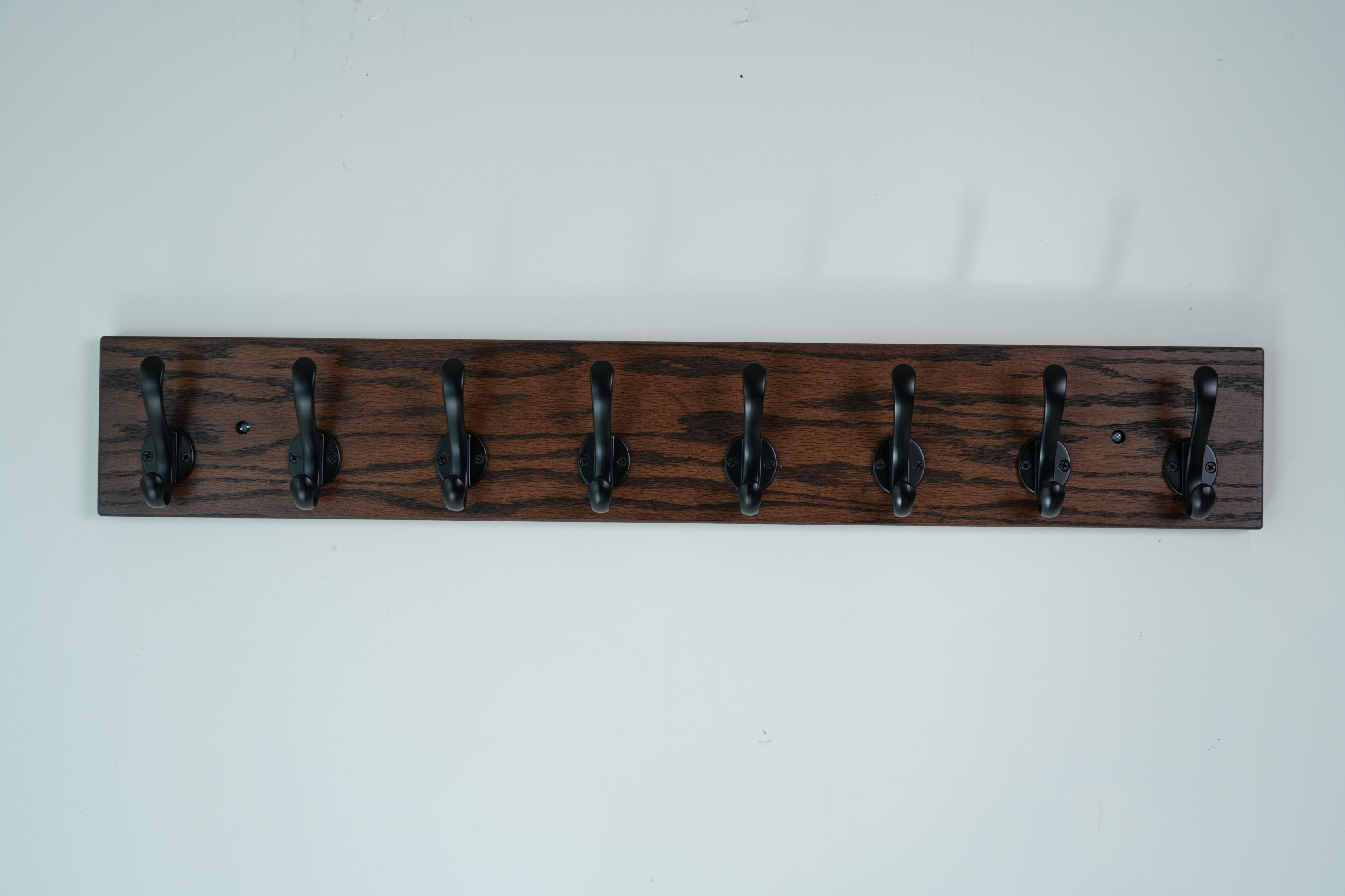 Wooden coat rack with five hooks on a white wall