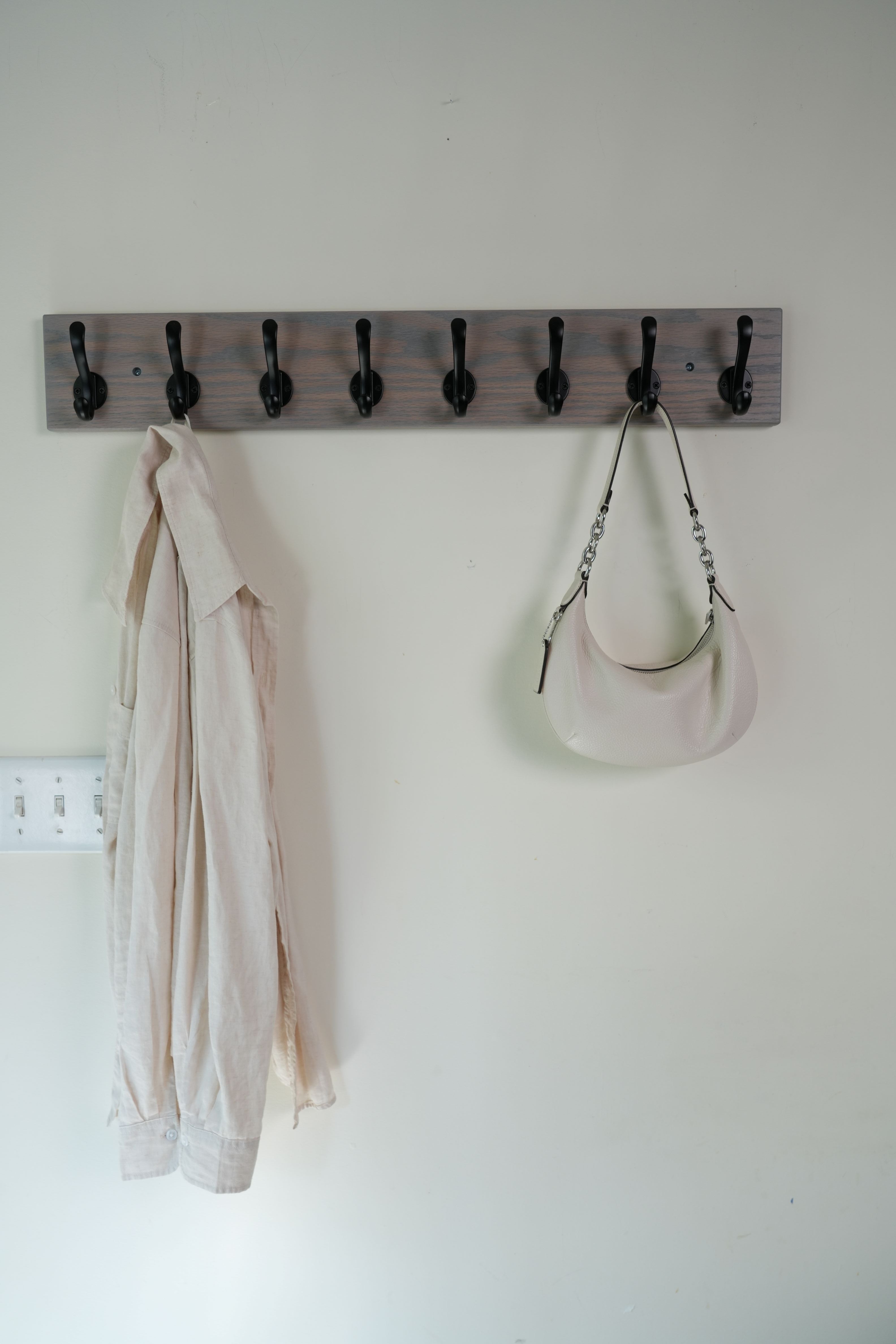 Wooden wall hook with multiple hooks on a white wall.