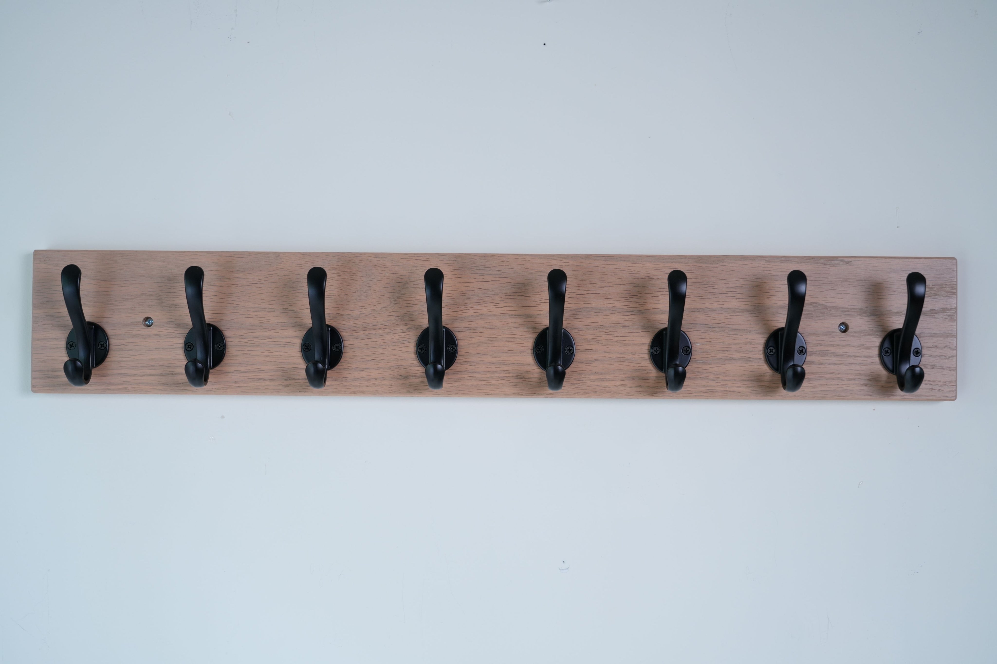 Wooden wall hook rack with black hooks on a white background