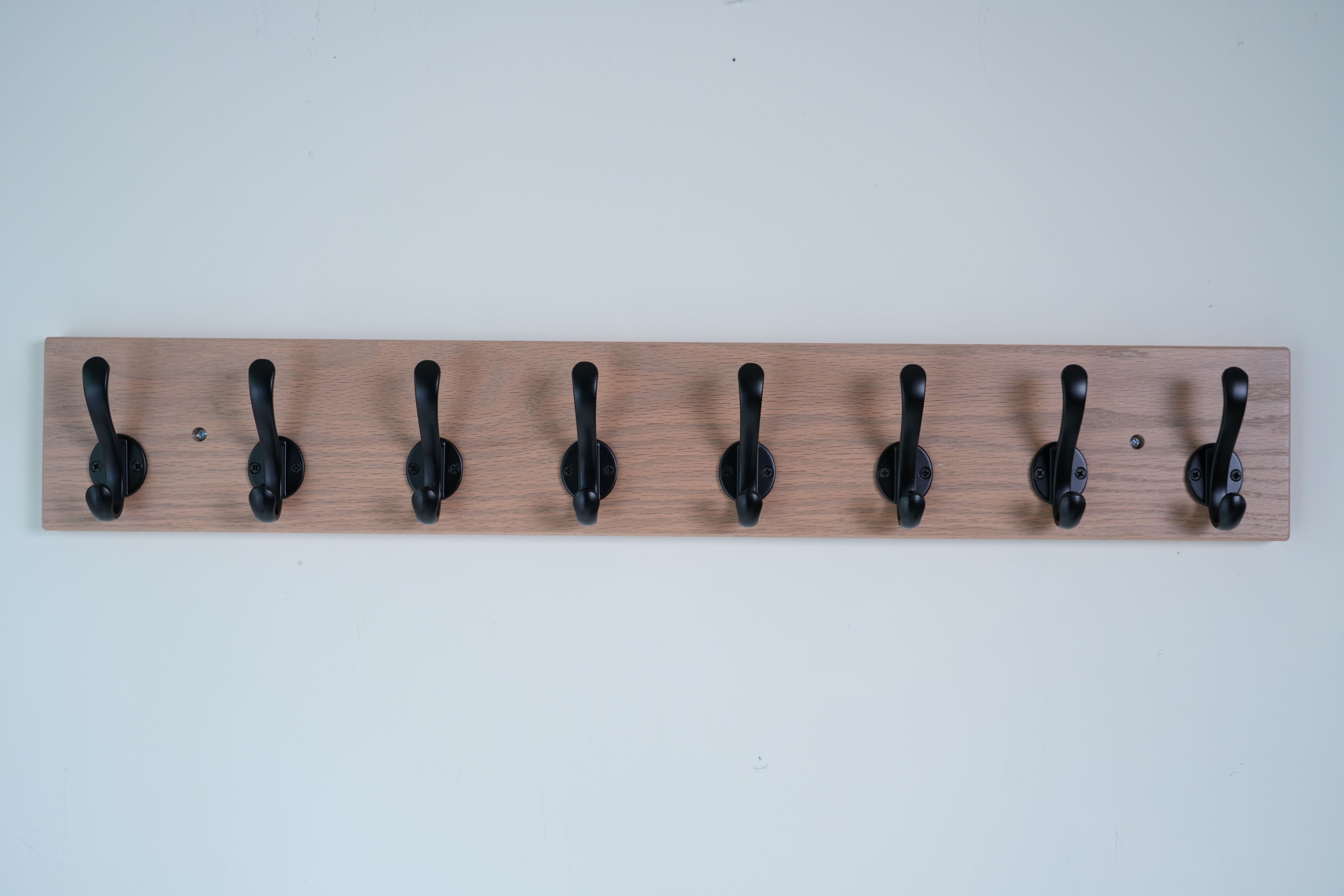 Wooden wall hook rack with black hooks on a white background