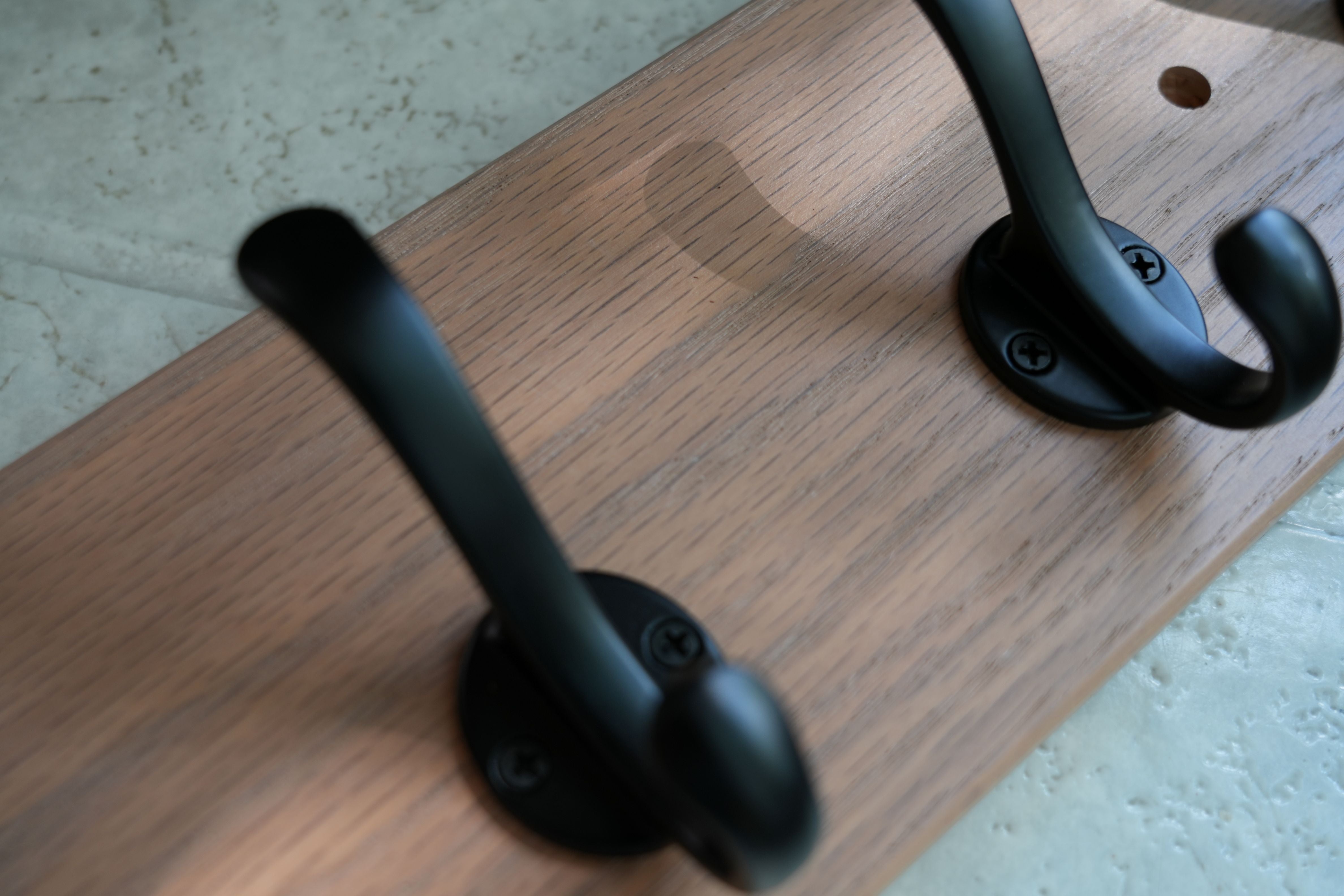 Two black hooks on a wooden surface