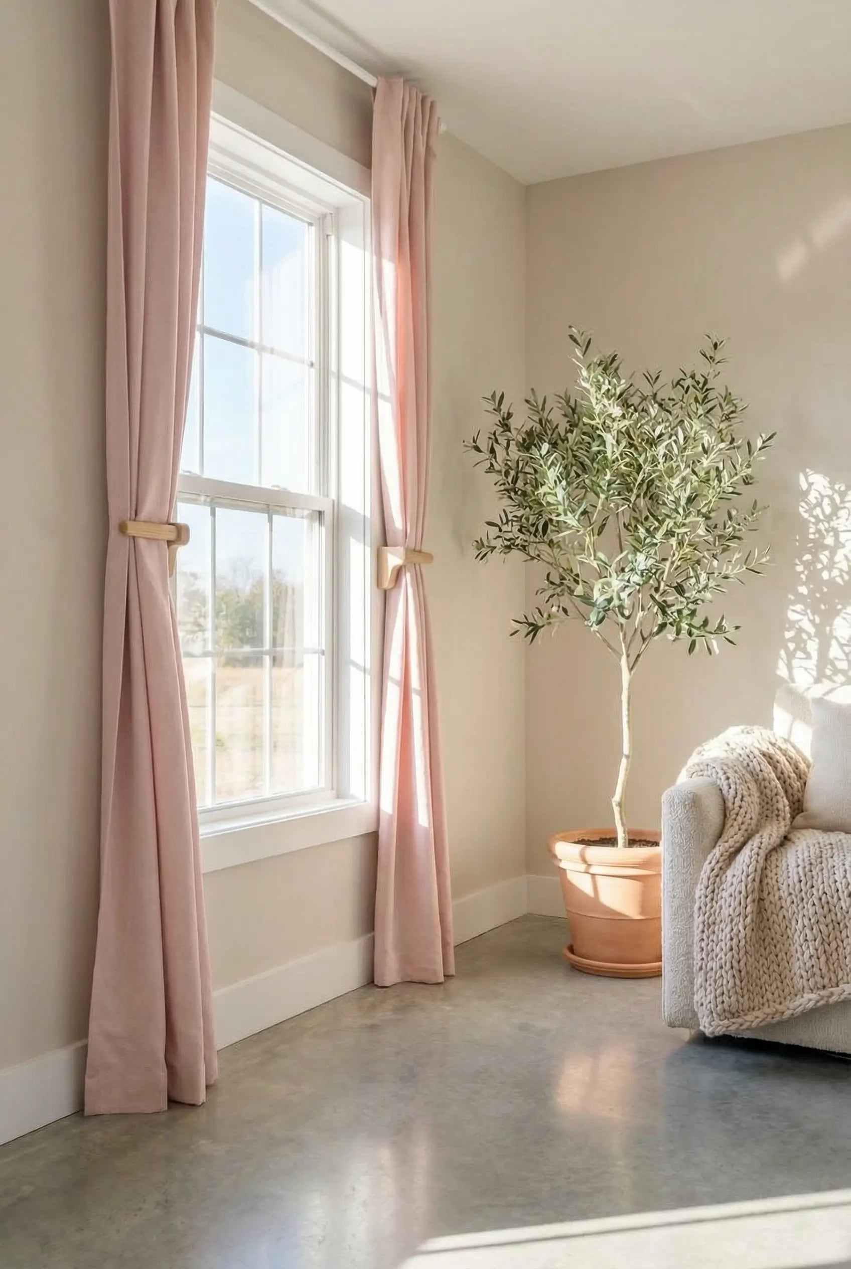 Living room with pink curtains, a plant, and a sofa.