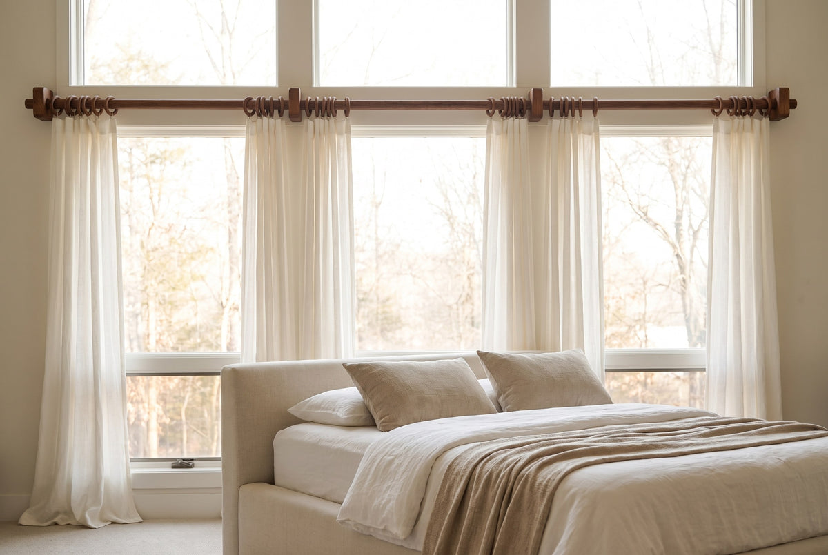 Ultra long brown oak curtain rod with square brackets above a wide bedroom window